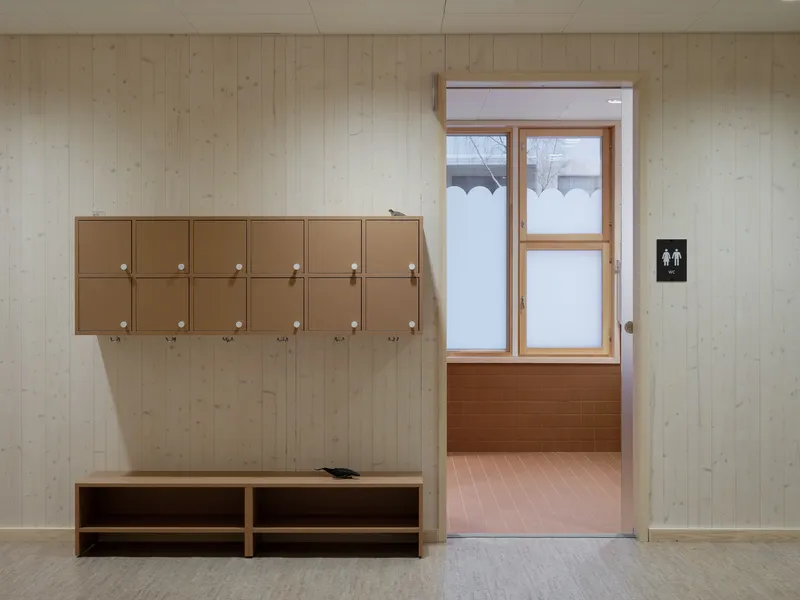 Mudroom with coat hooks and bench opening to snow-covered vestibule beyond