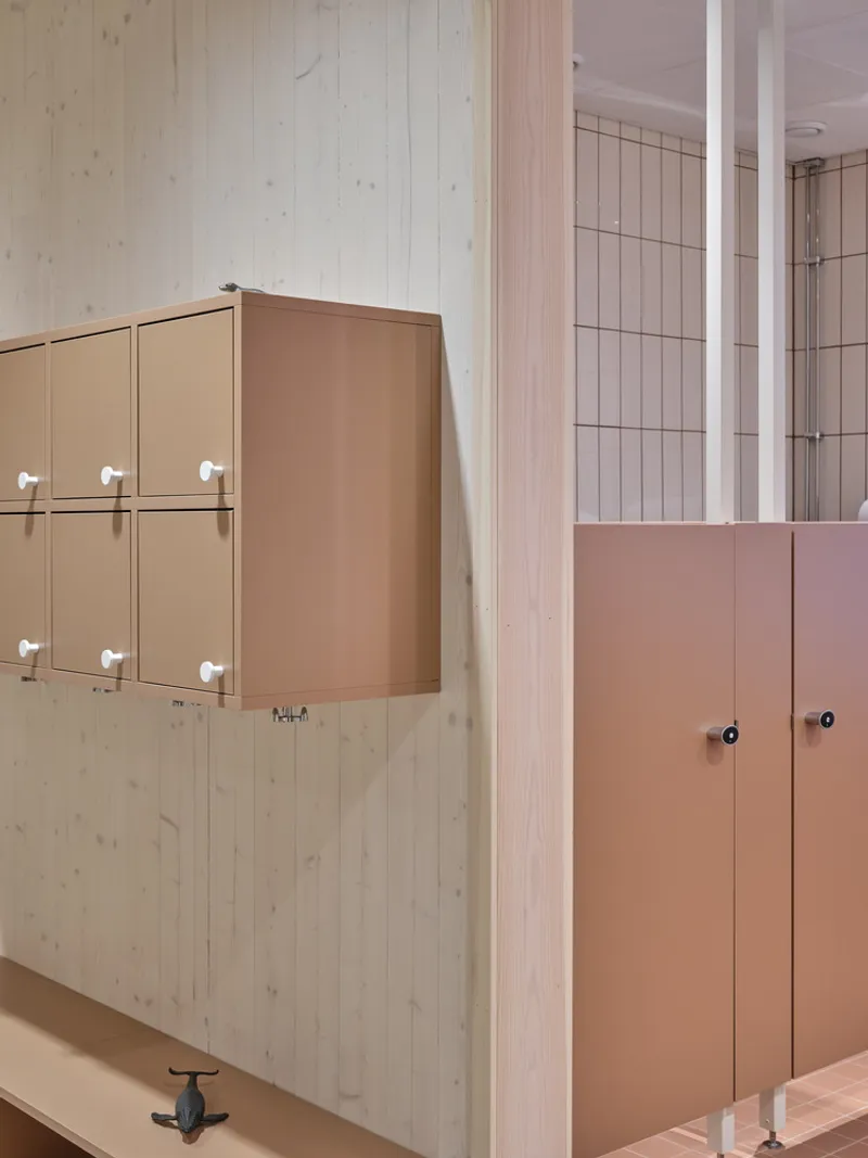 Detail of tan locker units on timber wall adjacent to tiled washroom entry