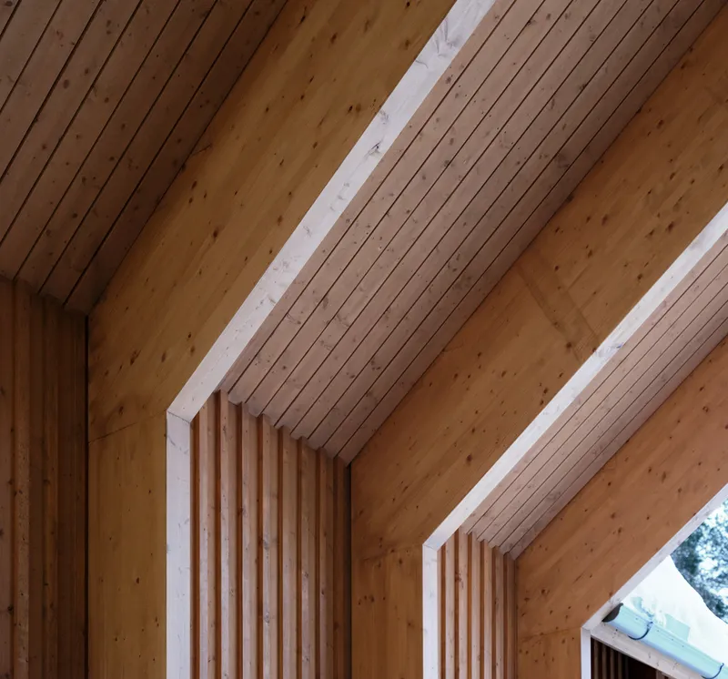 Sloped timber ceiling with exposed beams and recessed skylights running between ribbed wood panels