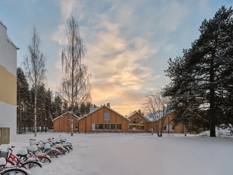 View across snow-covered field with bicycles in foreground and timber gabled buildings at sunset