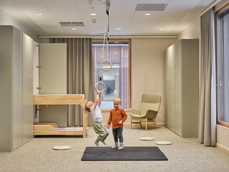 Playroom with bunk bed, suspended gymnastics rings, and two children on a terrazzo floor