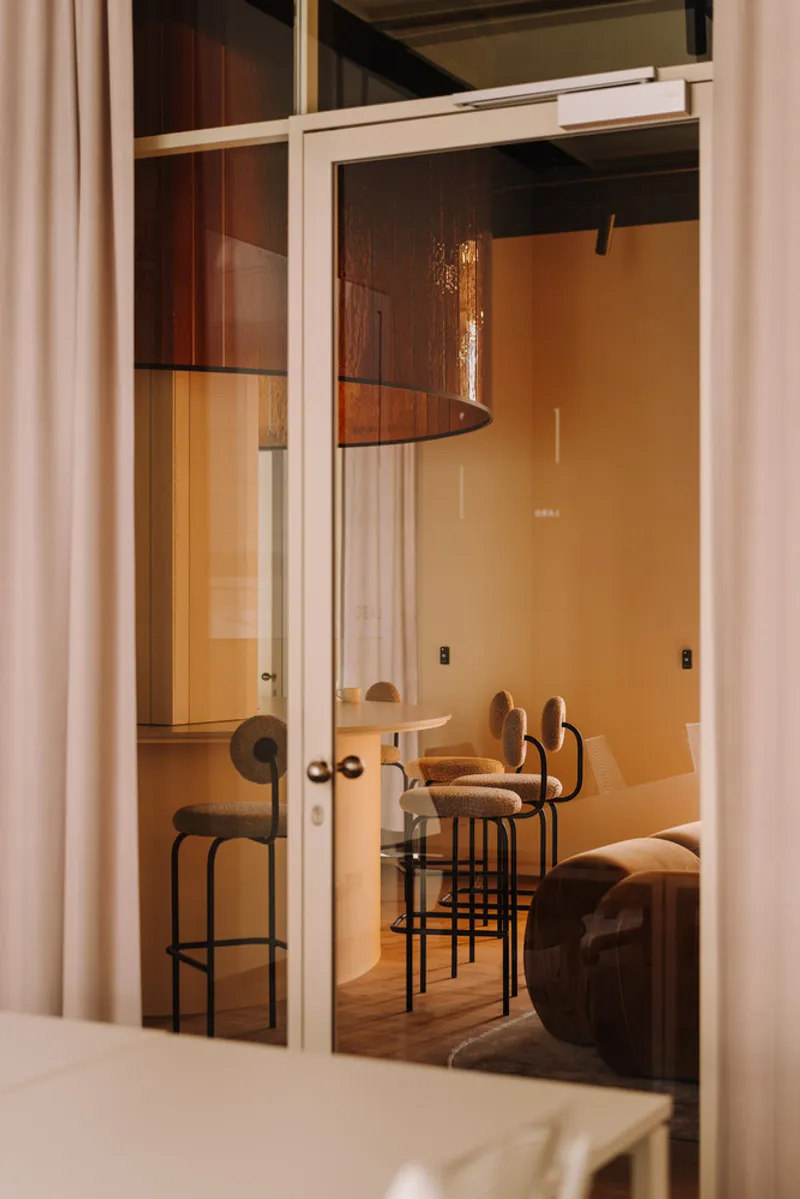 View through open glass door showing bar stools and copper pendant reflected in the glazing