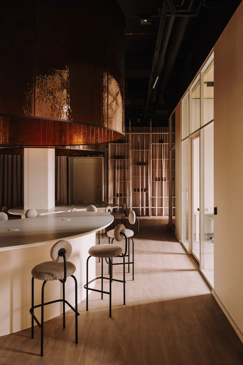 Narrow corridor along bar counter with upholstered stools and vertical metal rod display screen