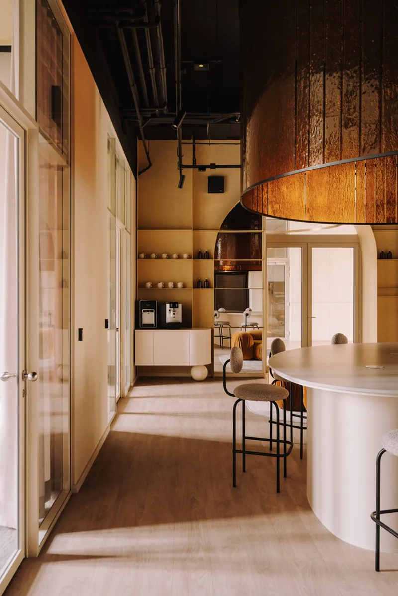 Interior passage with curved counter and timber pendant light leading to shelved service area