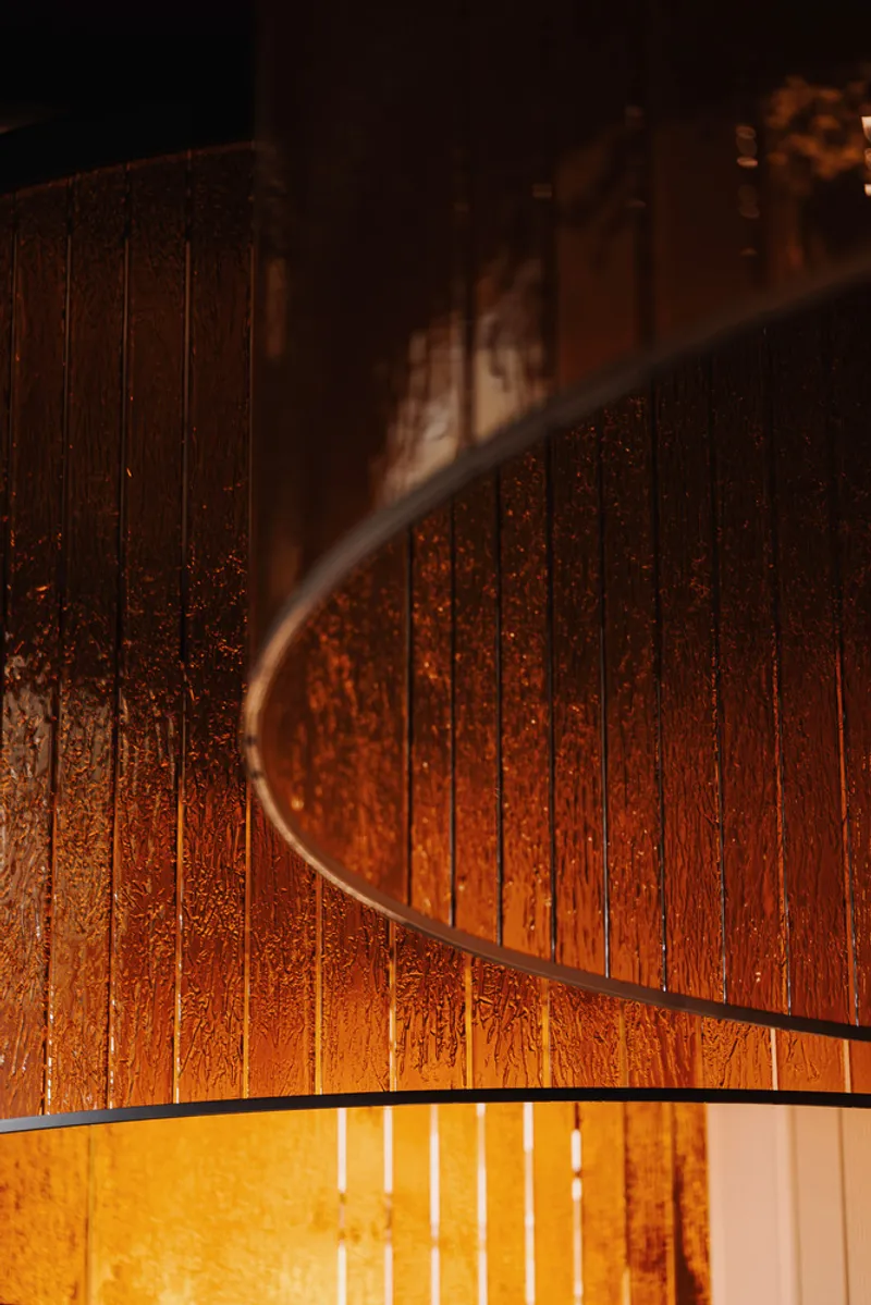 Close-up of curved vertical timber cladding with warm illumination from below