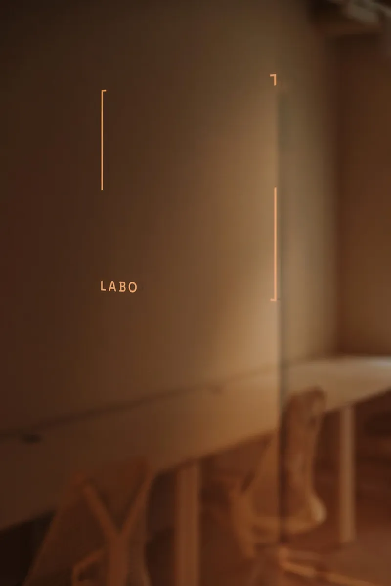 Glass door with illuminated lettering and vertical linear lights on the wall behind