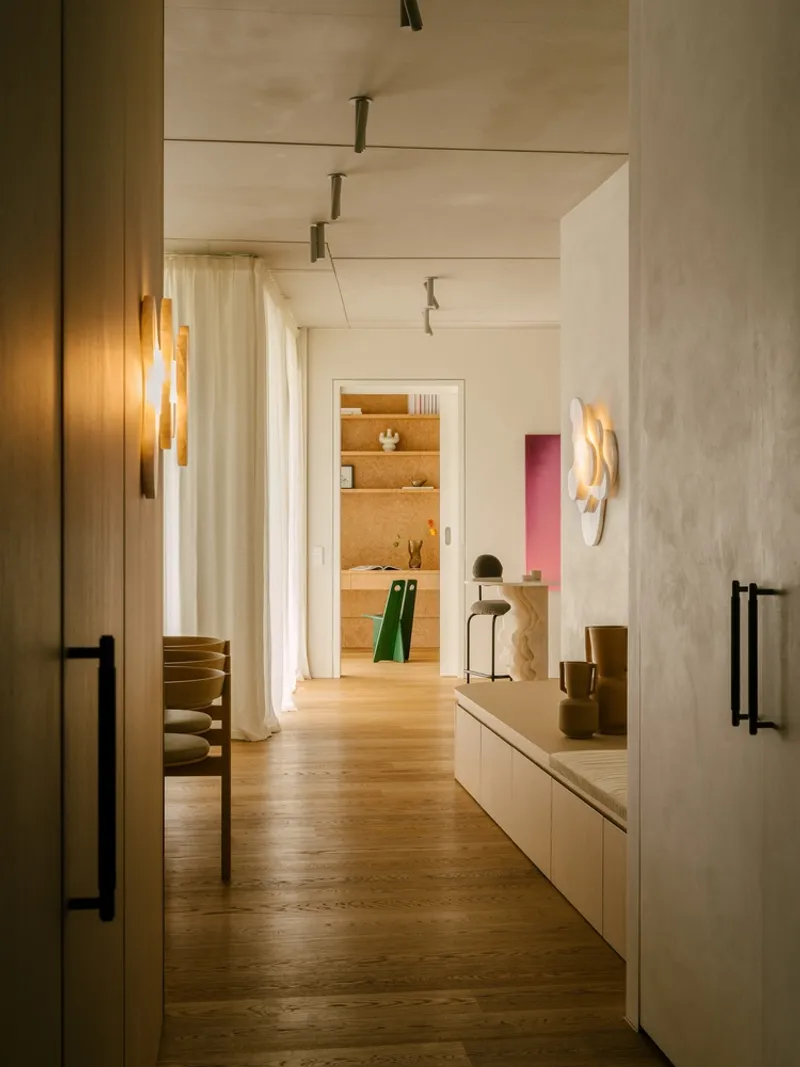 Corridor view through doorways revealing oak flooring and warm wall sconces in soft evening light