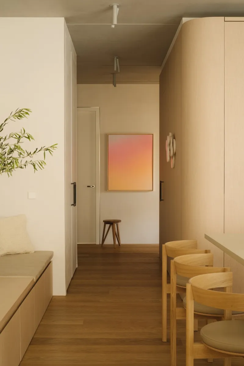 Hallway view toward a gradient painting on the wall with a wooden stool beneath