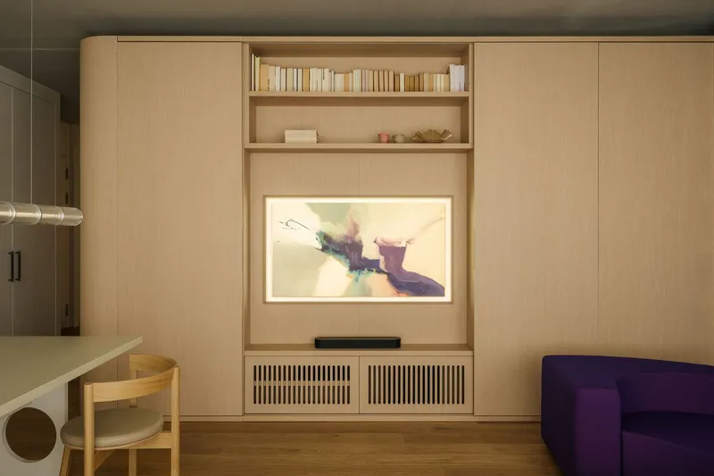 Media wall with built-in shelves, screened cabinet vents, and framed artwork above a soundbar