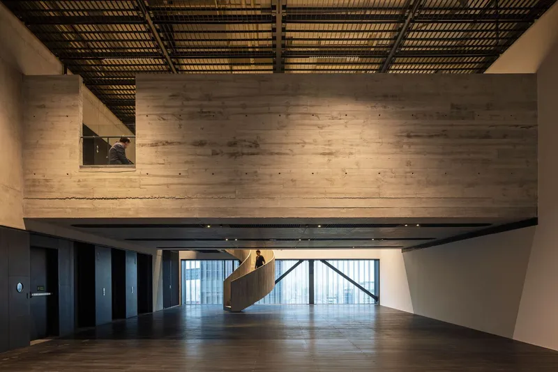 Double-height interior with timber-clad volumes and slatted ceiling grid filtering daylight from above