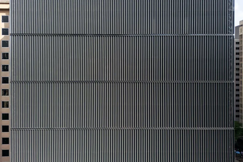 Facade detail of vertical metal fins arranged in horizontal bands across multiple floors