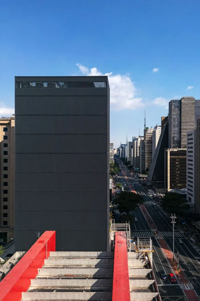 Vertical corrugated metal facade rising above a wide avenue in daytime