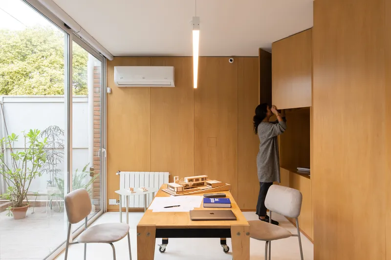 Workspace with timber walls and a mobile table looking onto a small planted terrace