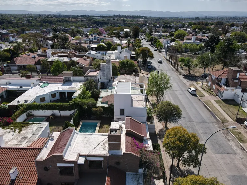 Aerial view of the white volumes inserted into a residential neighborhood with tree-lined streets