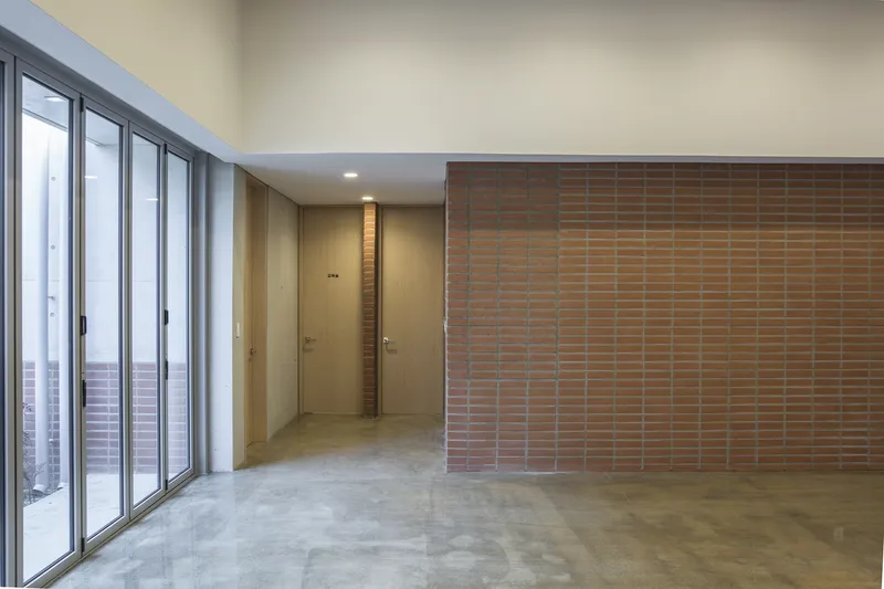 Open interior space with terracotta brick screen wall and sliding glass doors to an exterior stair