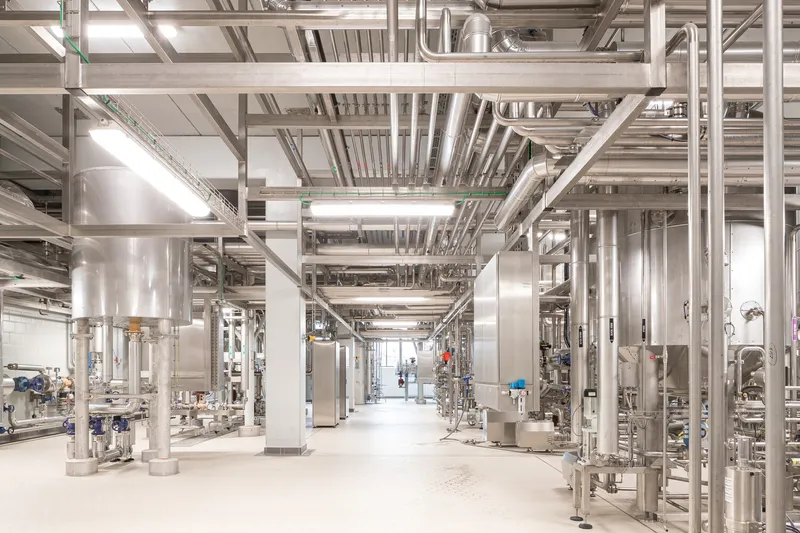 Interior view of the production hall with exposed steel framework and stainless processing equipment