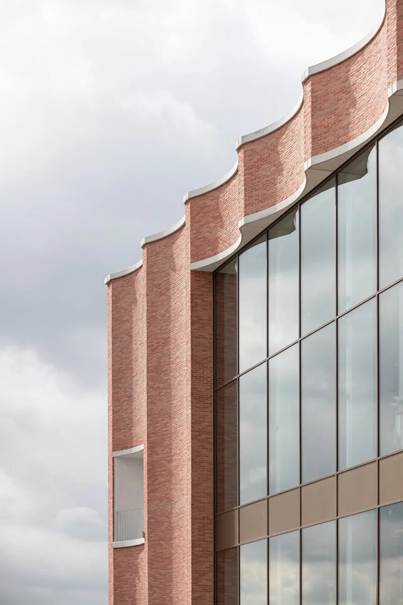 Close-up of the pleated brick parapet edge meeting the vertical glass curtain wall