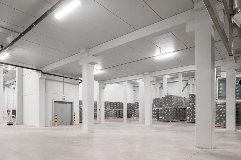 Concrete beam and column structural grid in warehouse space with palletized goods and service elevator