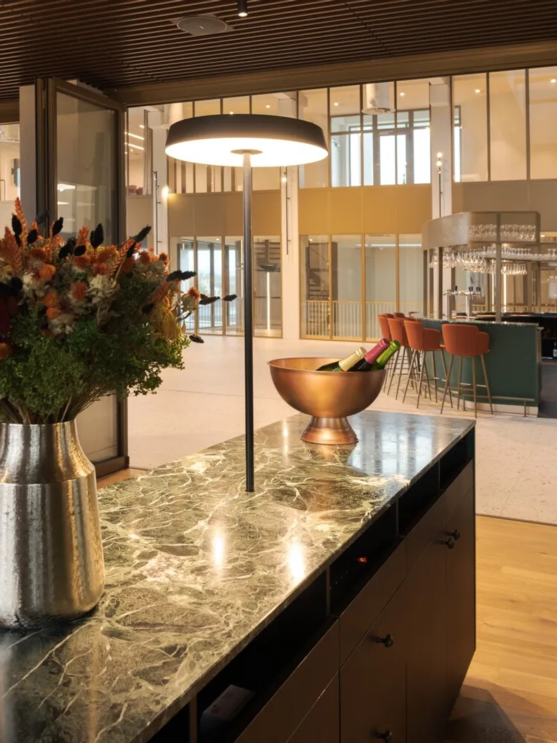 Green marble countertop island with copper bowl centerpiece and dried flower arrangement beneath a circular pendant lamp