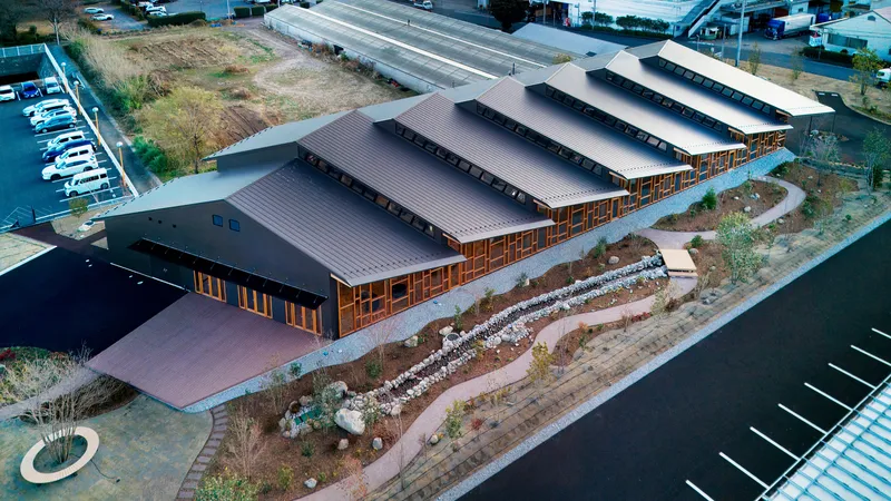 Aerial view of the stepped metal roof volumes with timber-framed glazing and landscaped garden beds in winter