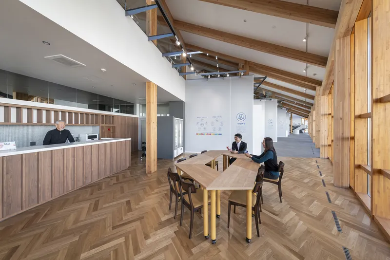 Open dining area with exposed timber beams, herringbone flooring, and two people seated at a table