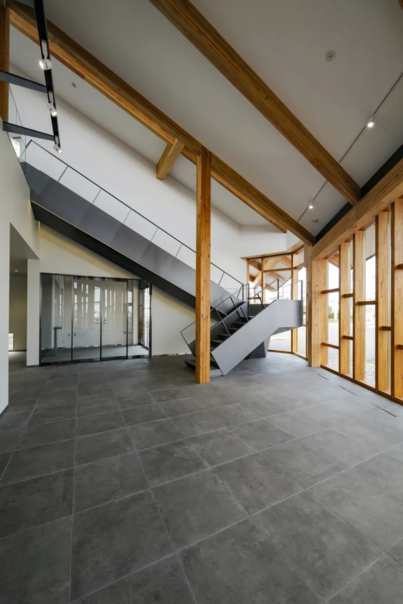 Lobby with folded steel stair sculpture rising through a volume framed by timber columns