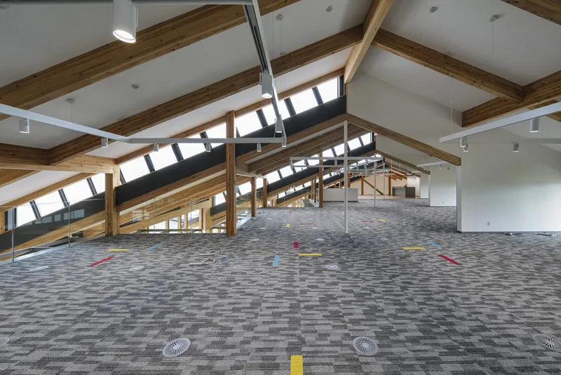 Open office floor with exposed timber rafters and clerestory windows along the pitched ceiling