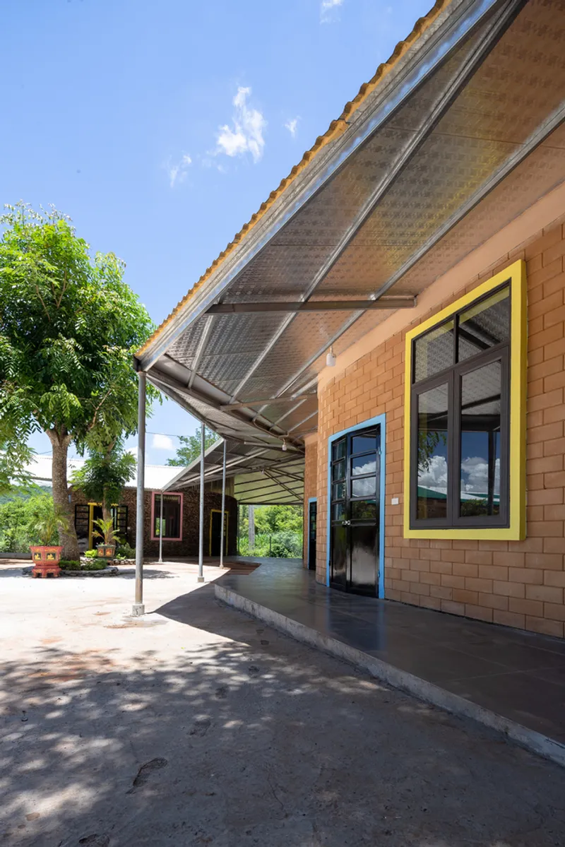 Angled view of the translucent corrugated canopy supported by slender steel columns in afternoon sun