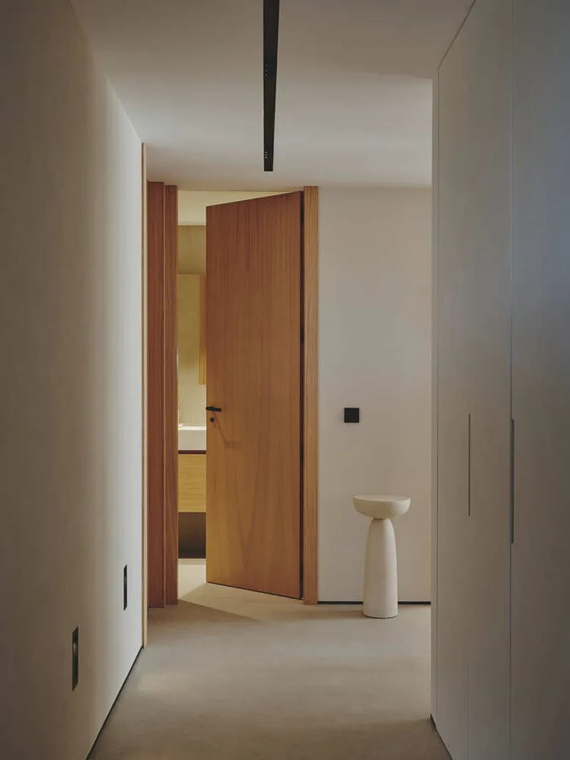 Narrow corridor featuring timber door jamb and white sculptural side table on polished concrete floor
