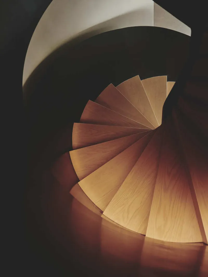 Overhead view of the spiral staircase showing radiating timber treads illuminated from above