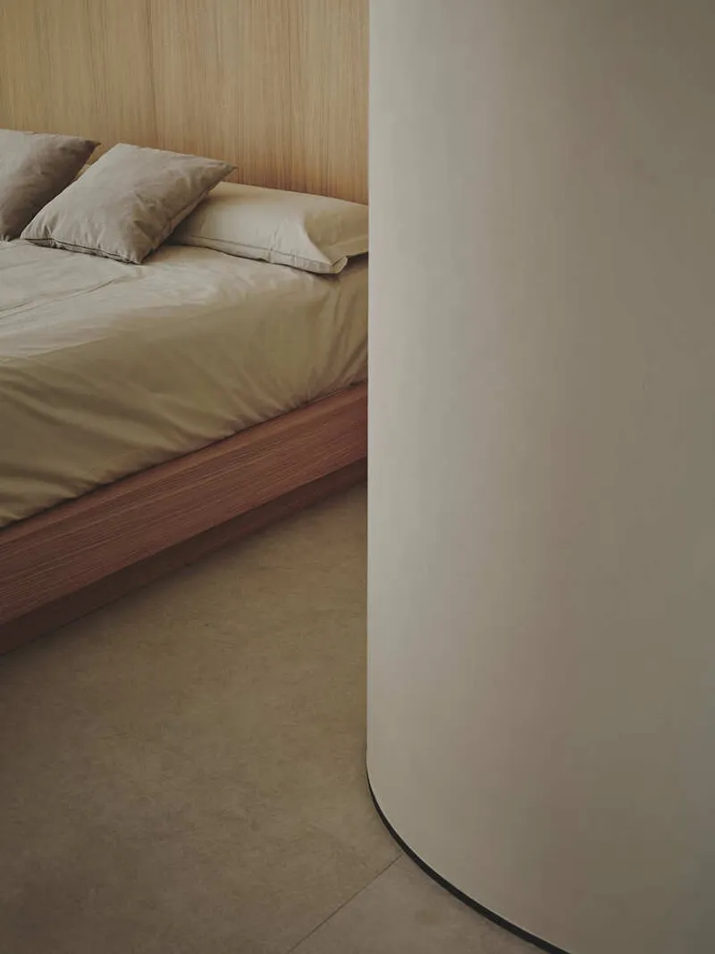 Corner detail showing a rounded white column next to a platform bed with timber cladding behind