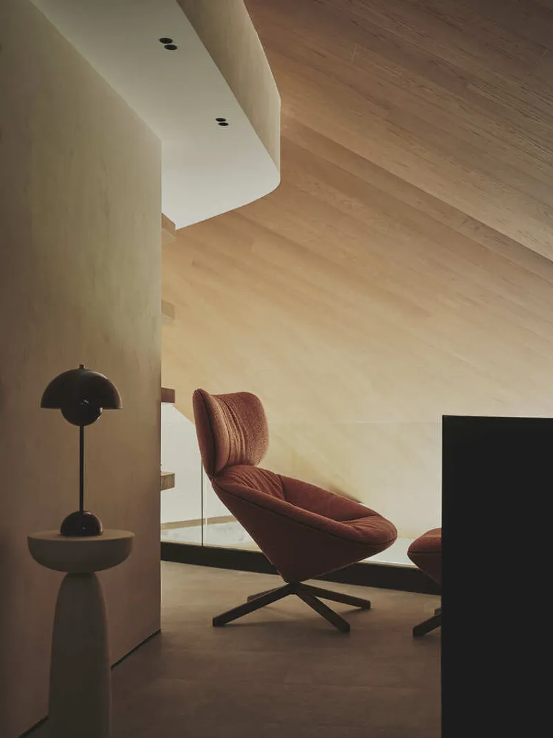 Living area with curved plaster wall and timber ceiling soffit in afternoon light