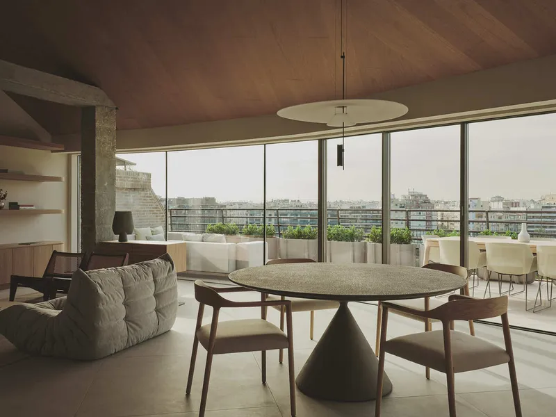 Open-plan living and dining space with full-height glazing and planters on the terrace beyond