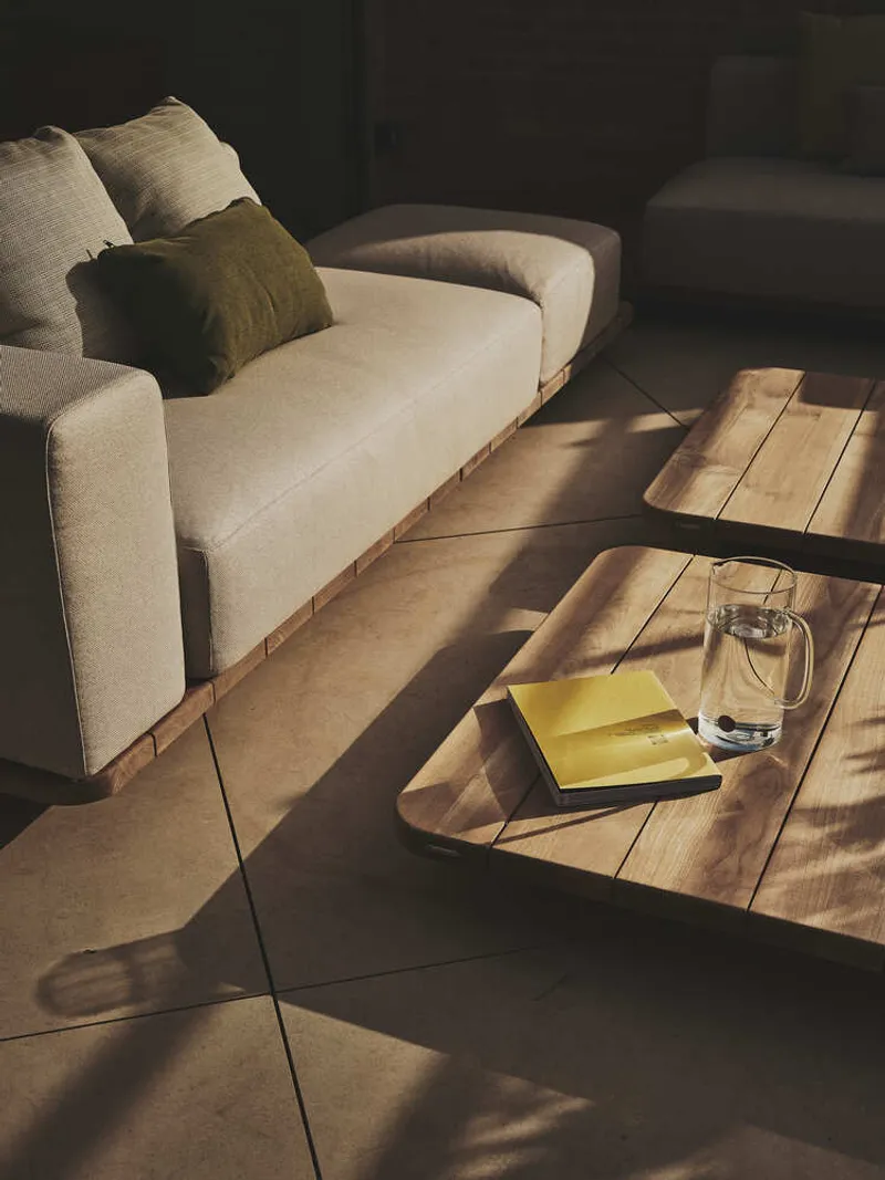 Timber coffee table with book and glass casting sharp afternoon shadows across the tiled floor
