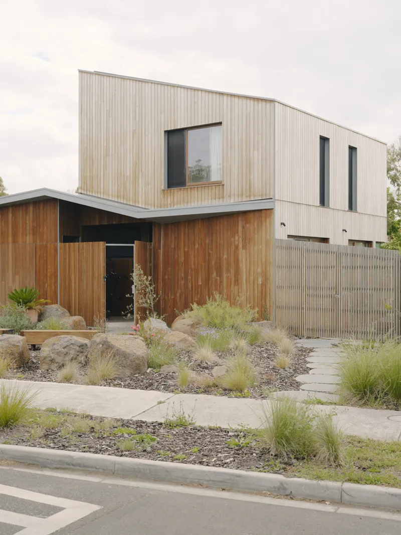 Entry path with concrete pavers through drought-tolerant grasses leading to the timber and metal facade