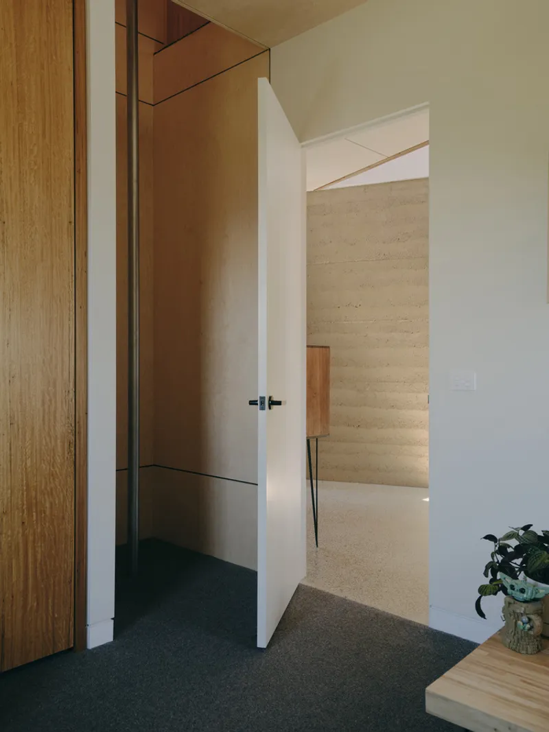 View through doorway showing polished concrete floor and plywood wall panels beside timber joinery
