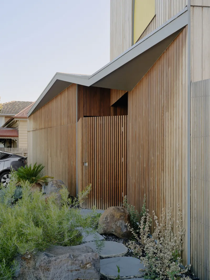 Vertical timber slat facade with angular zinc roof above a planted rockery garden