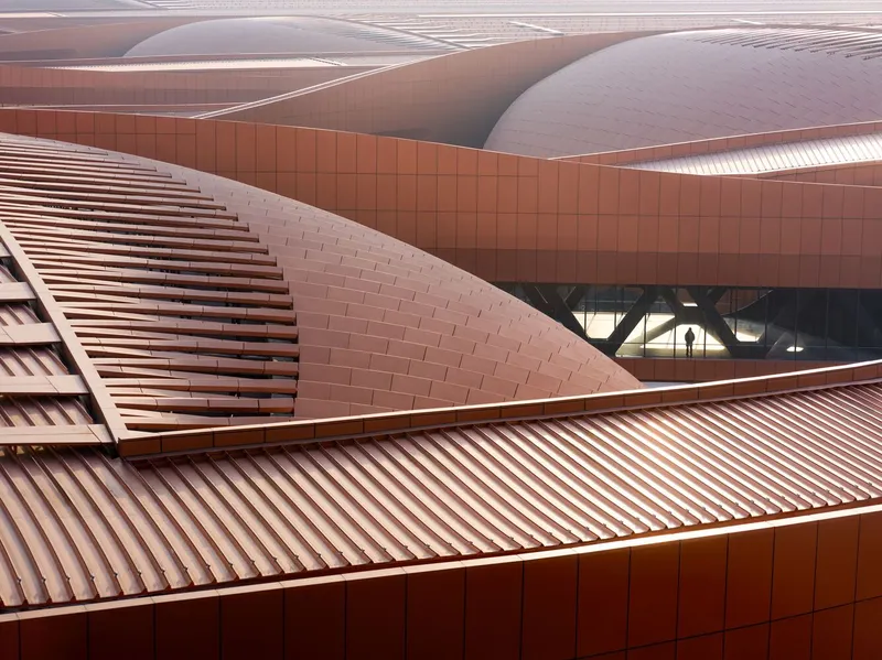 Overlapping copper panel surfaces with varied textures of louvres, tiles and corrugation meeting at angular edges