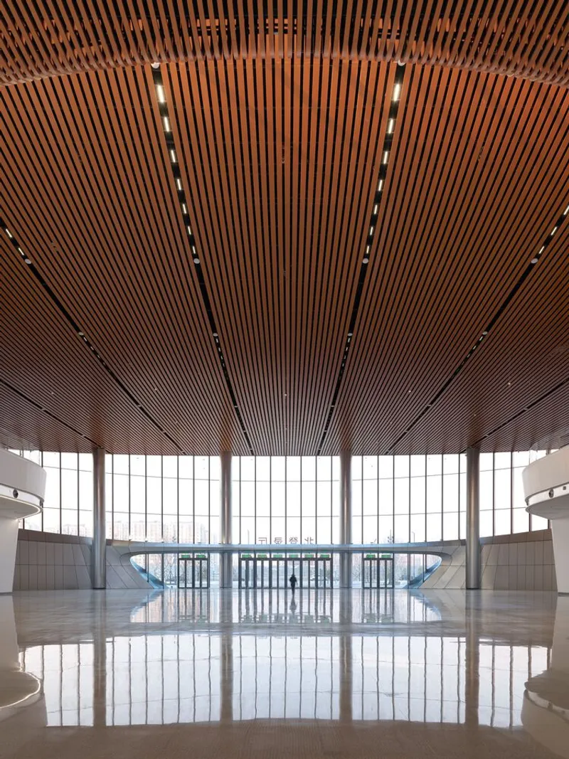 Interior lobby with radiating timber ceiling slats and floor-to-ceiling glazing reflecting on polished floor