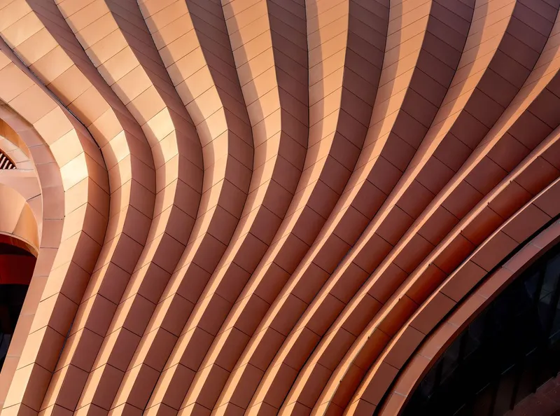 Close-up of undulating terracotta panel facade forming rhythmic waves across the surface
