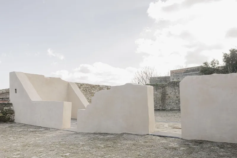 Cluster of white stucco walls with folded rooflines against a cloudy sky