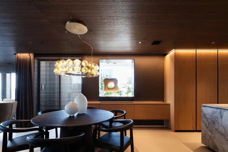Dining area with round black table and pendant chandelier near framed window with daylight