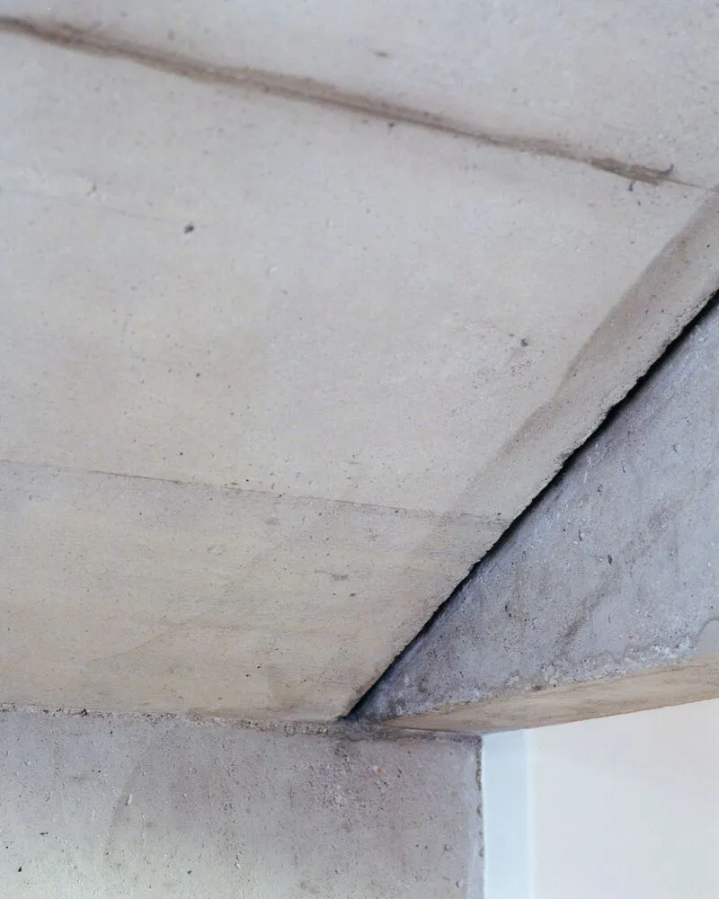 Detail of concrete ceiling and wall junction showing formwork joints and raw surface texture