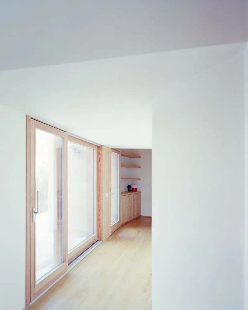 White corridor with timber framed glazing leading to a built-in storage area
