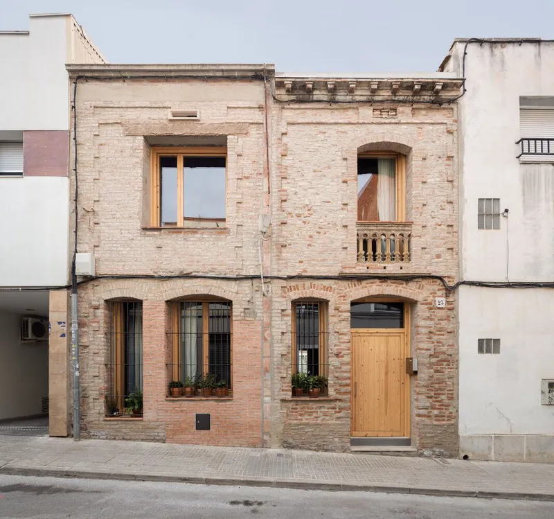 Street facade showing exposed brick walls with timber window frames and a small balustrade balcony