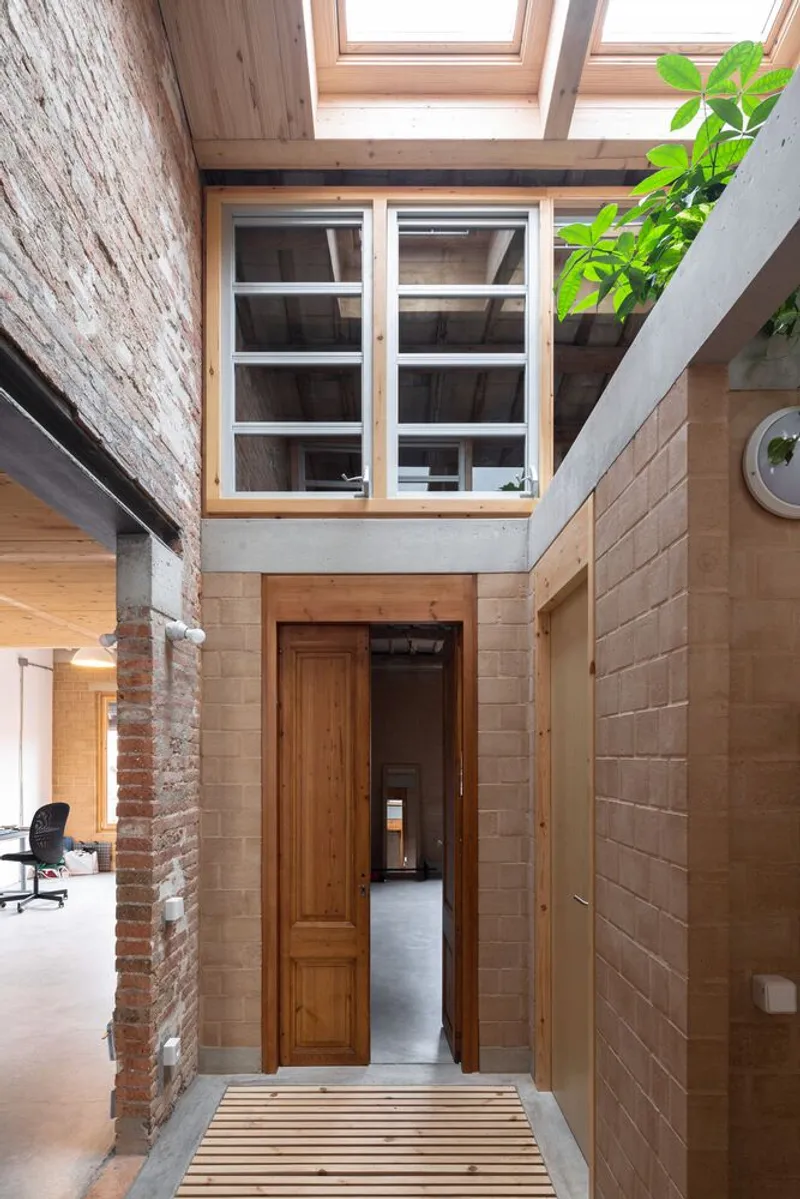 Interior courtyard with exposed brick wall, timber door, and skylights overhead with a potted plant
