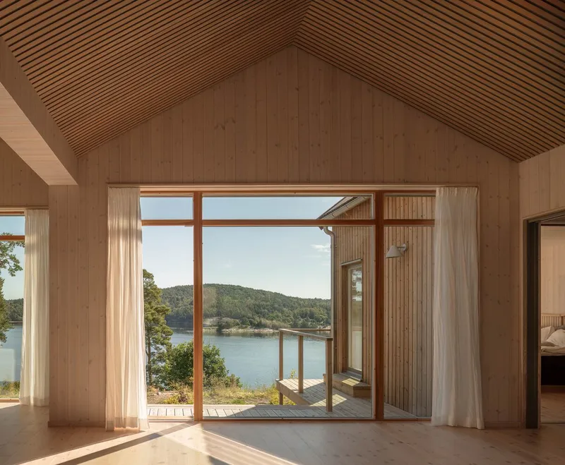 Interior with slatted wood ceiling and glazed doors framing a view of the waterfront landscape