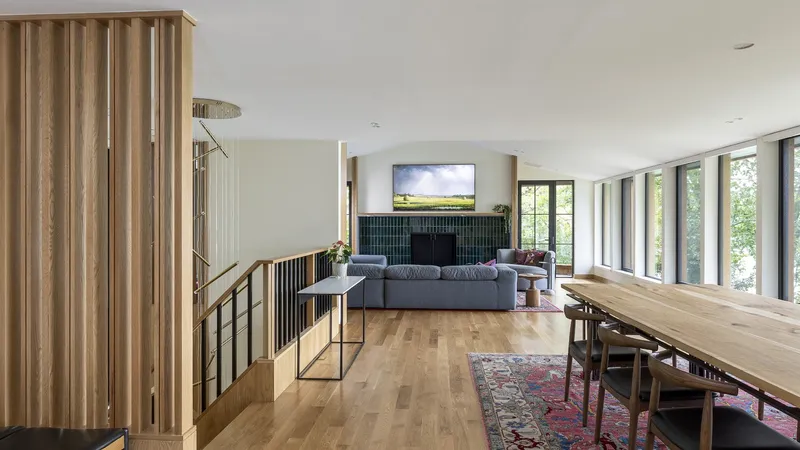 Open-plan living and dining space with timber balustrade and views to surrounding forest