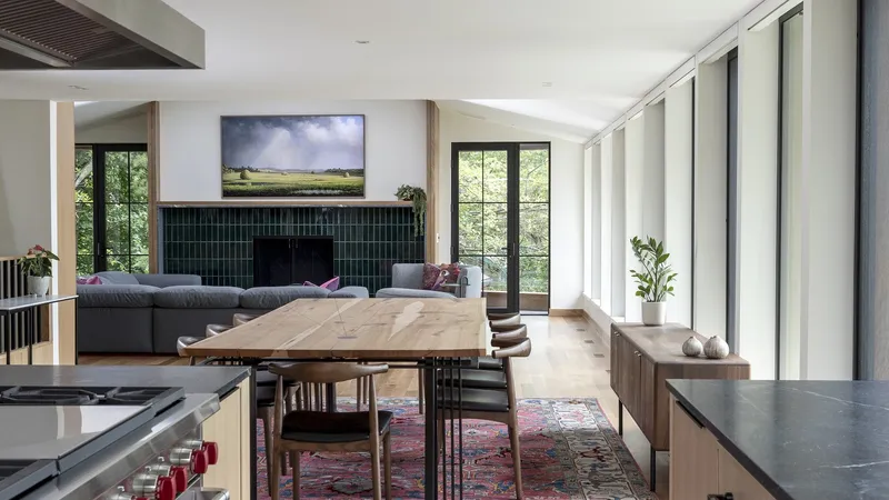 Combined kitchen and dining area with green herringbone tile backsplash and vertical white drapes