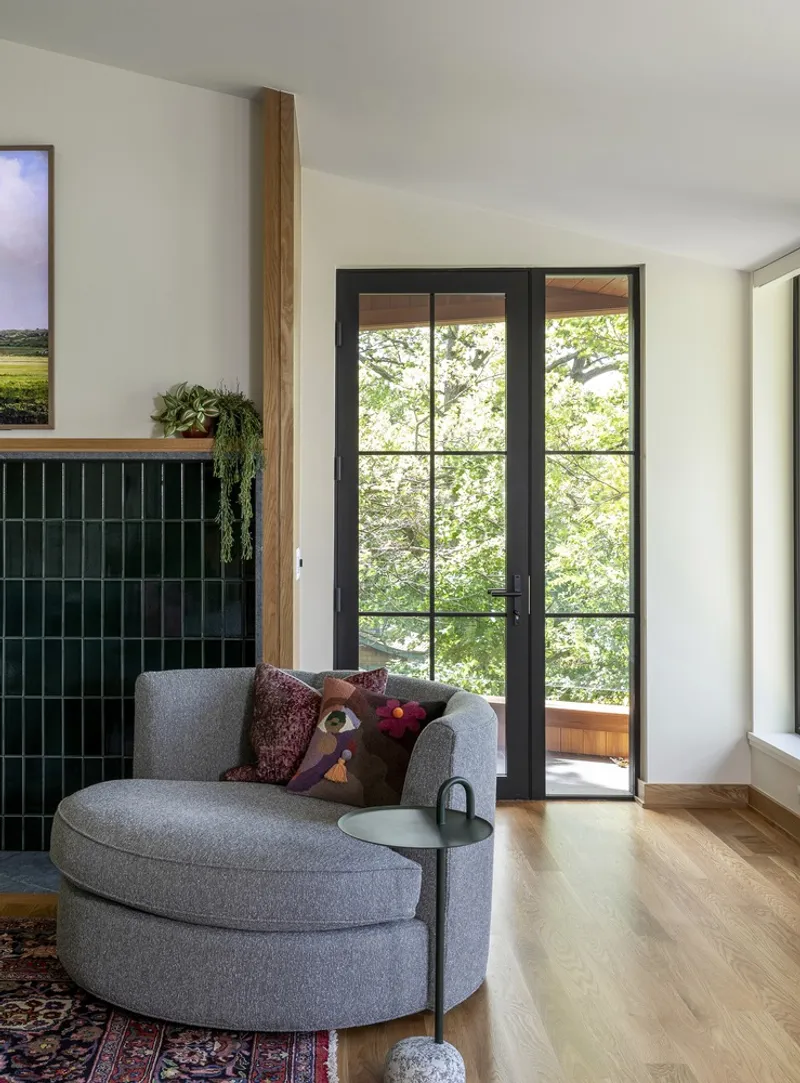 Living room with black steel-framed glass doors opening to a treed outdoor deck